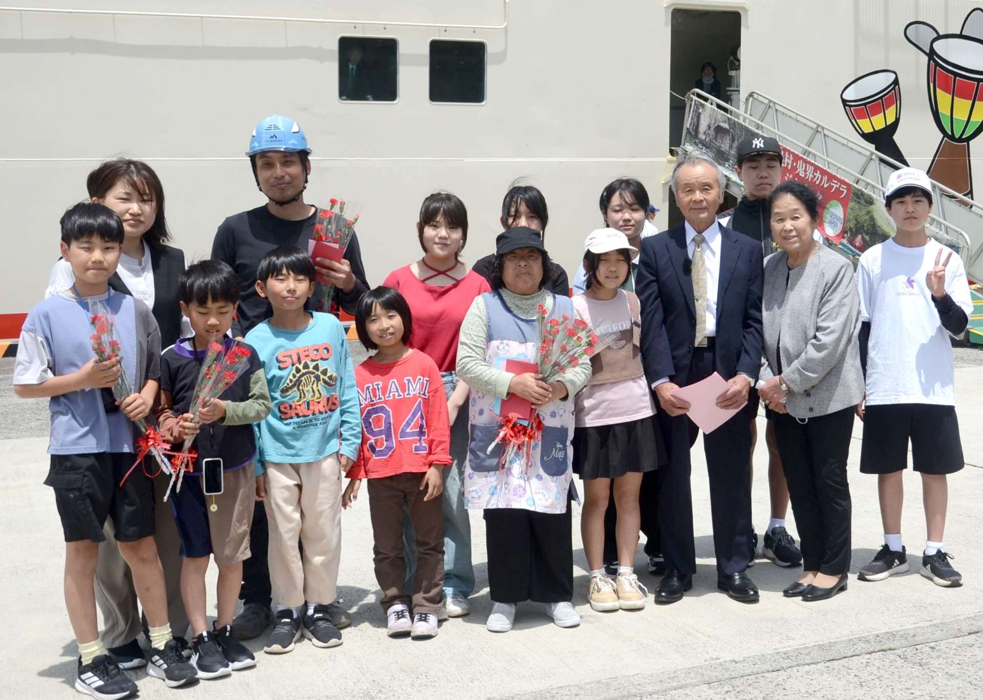カーネーションを渡して子どもらと記念撮影をする田知行義久さん＝１０日、三島村竹島