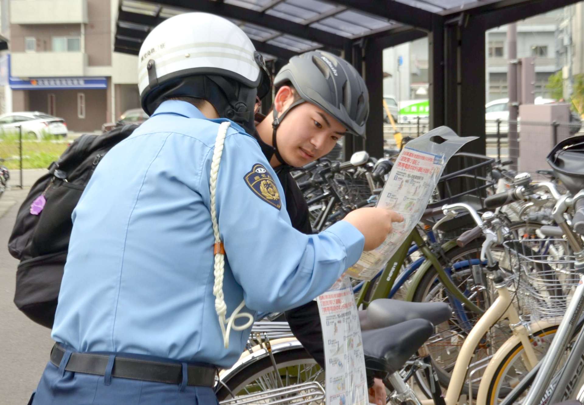 自転車利用者に安全運転を呼びかける警察官＝１２日、鹿児島市のＪＲ谷山駅