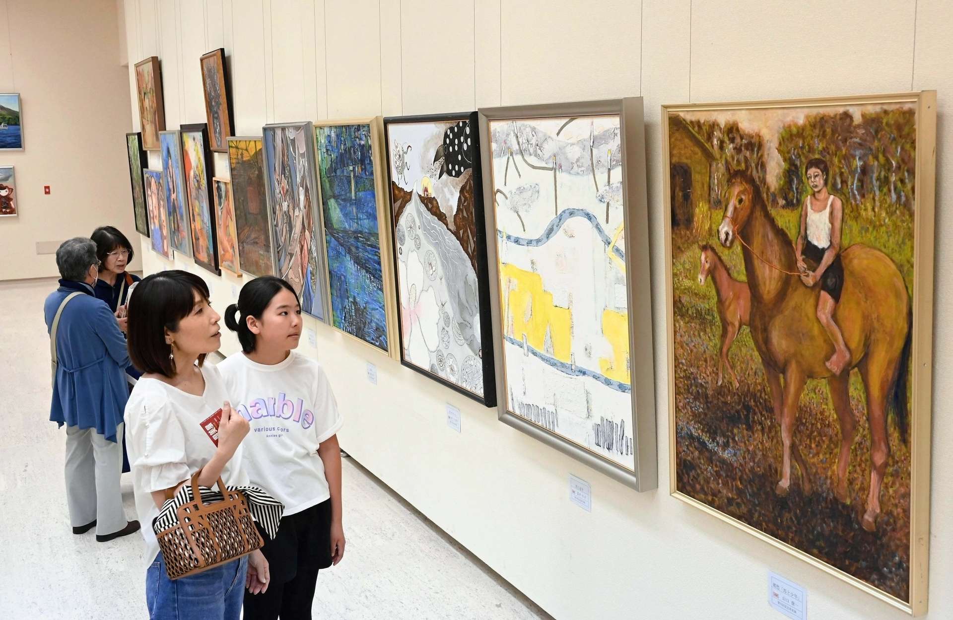 〈資料写真〉昨年の第70回記念県美展で、色彩豊かな作品に見入る来場者＝鹿児島市立美術館