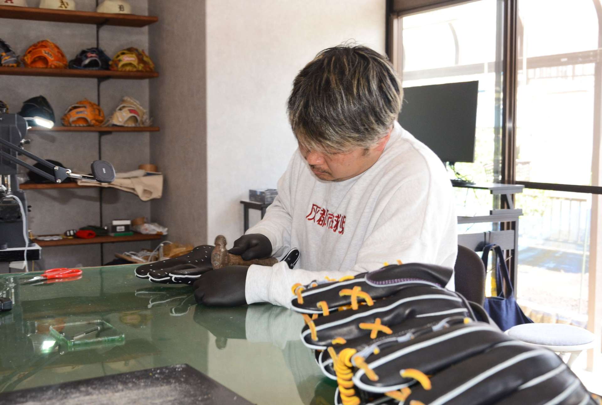 ハンマーを使いグラブの形を整える福迫一真さん＝鹿児島市