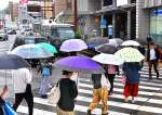 傘を差して、足早に交差点を渡る人たち＝１６日午後４時４０分、鹿児島市中央町