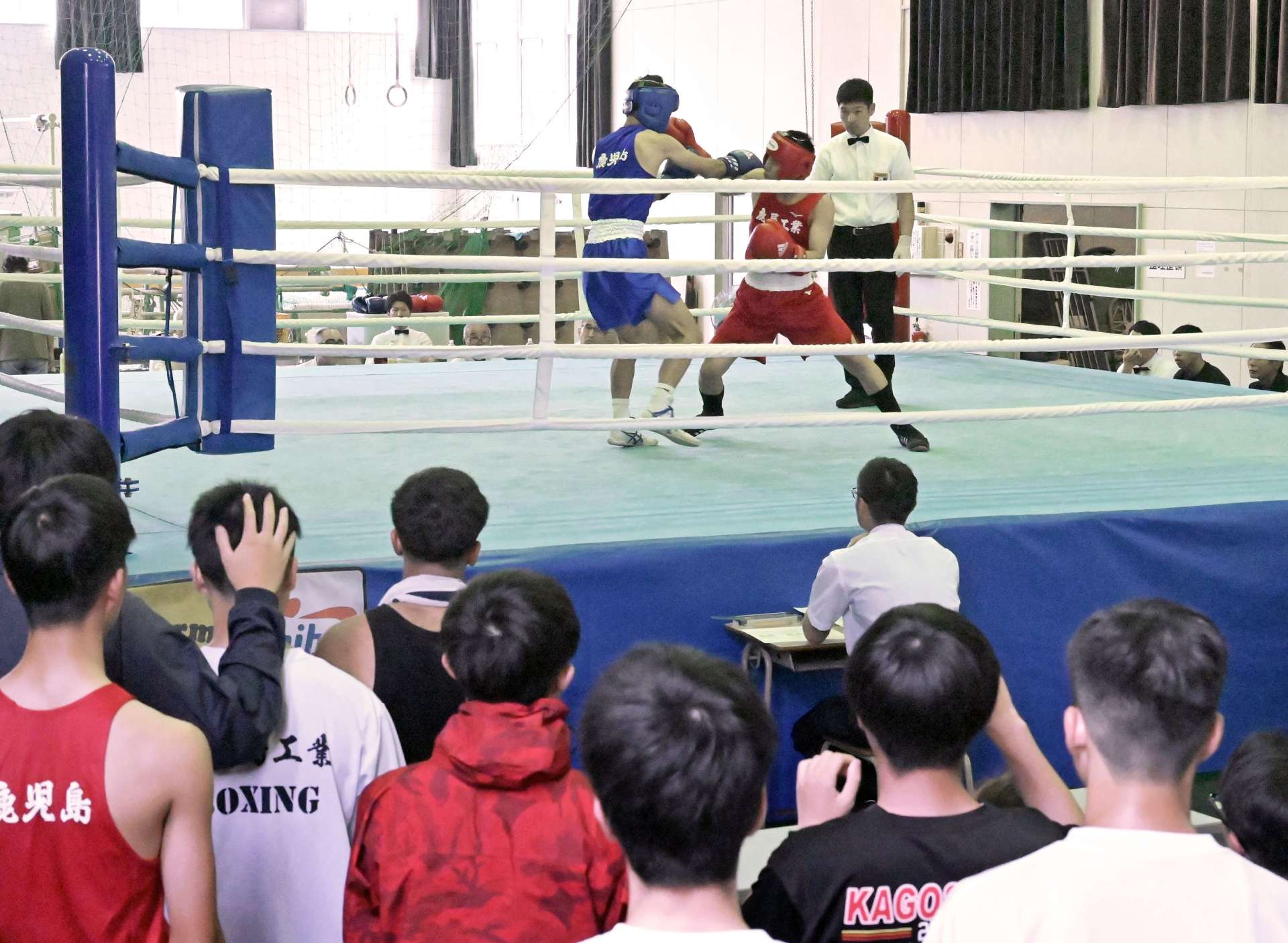 チームメートが見守る中、熱戦を繰り広げるボクシング競技の選手＝１６日、鹿児島市の県補助体育館