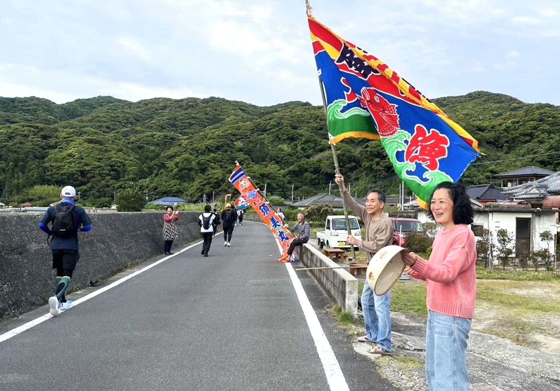 大漁旗を振ってランナーを応援する地元住民＝薩摩川内市下甑の手打