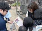 自分たちの写真が入った記念日新聞を受け取る来園者＝鹿屋市のかのやばら園