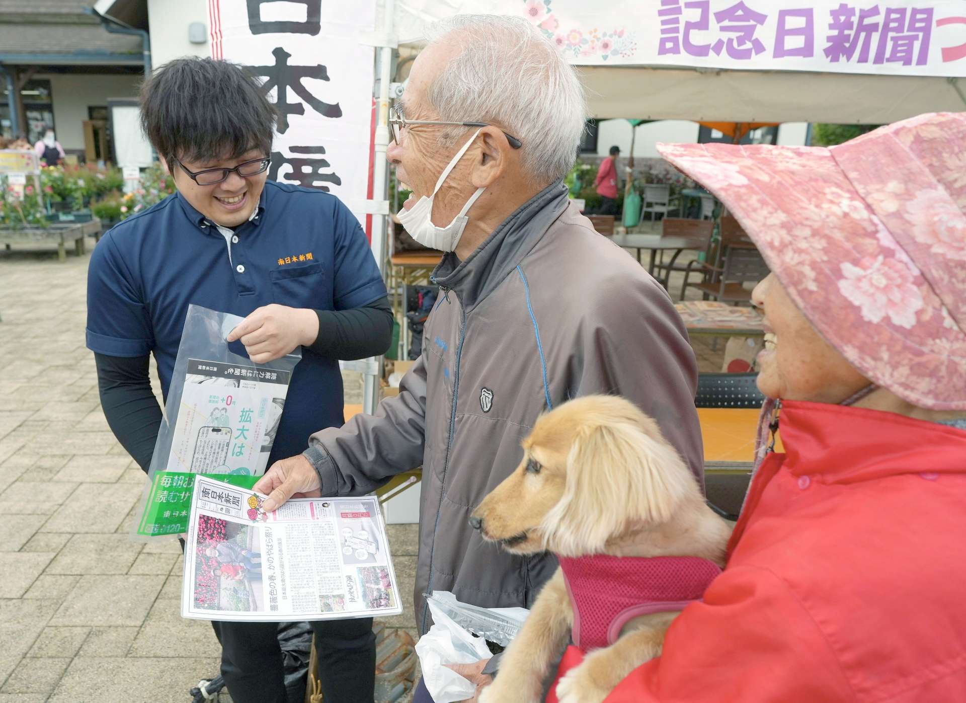 自分たちの写真が入った記念日新聞を受け取る来園者＝鹿屋市のかのやばら園