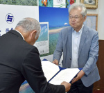 答申書を提出する国学院大学の梅川智也教授（右）＝１８日、与論町役場