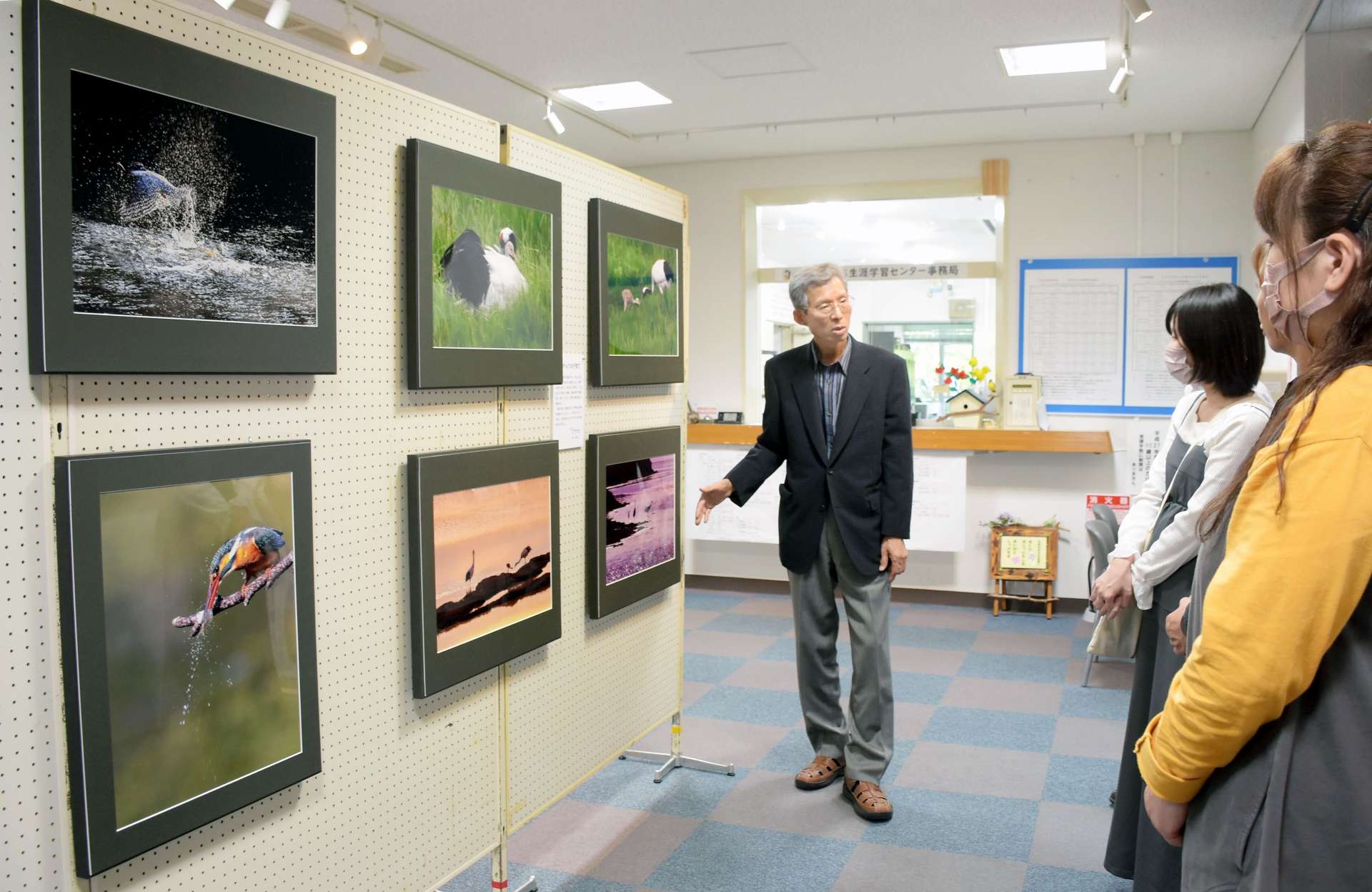 野鳥の生き生きとした姿を撮影した写真を解説する内野正さん（中央）＝志布志市文化会館