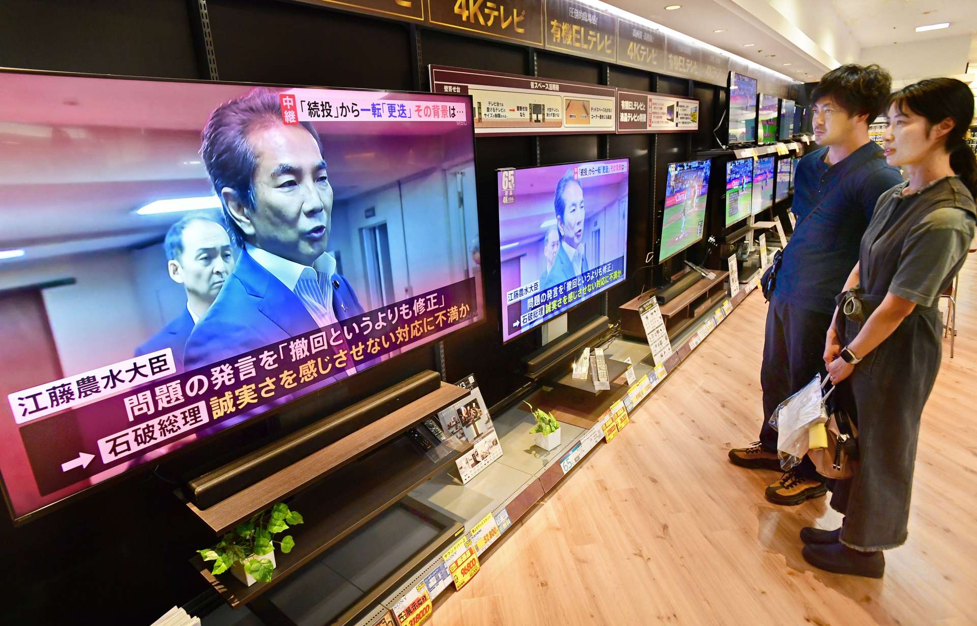 江藤拓農相の辞任を伝えるテレビ報道を見る人たち＝２１日午前１１時半すぎ、エディオン鹿児島山形屋店