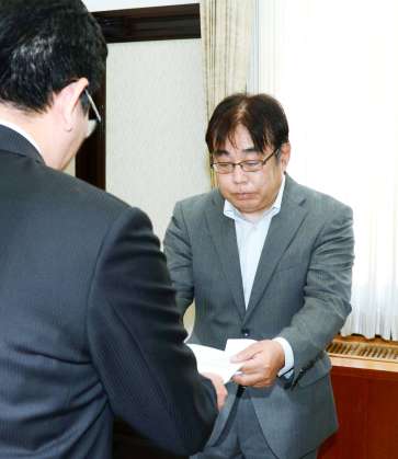 答申書を下鶴隆央・鹿児島市長に手渡す市特別職報酬等審議会の石塚孔信会長（右）＝２２日、鹿児島市役所