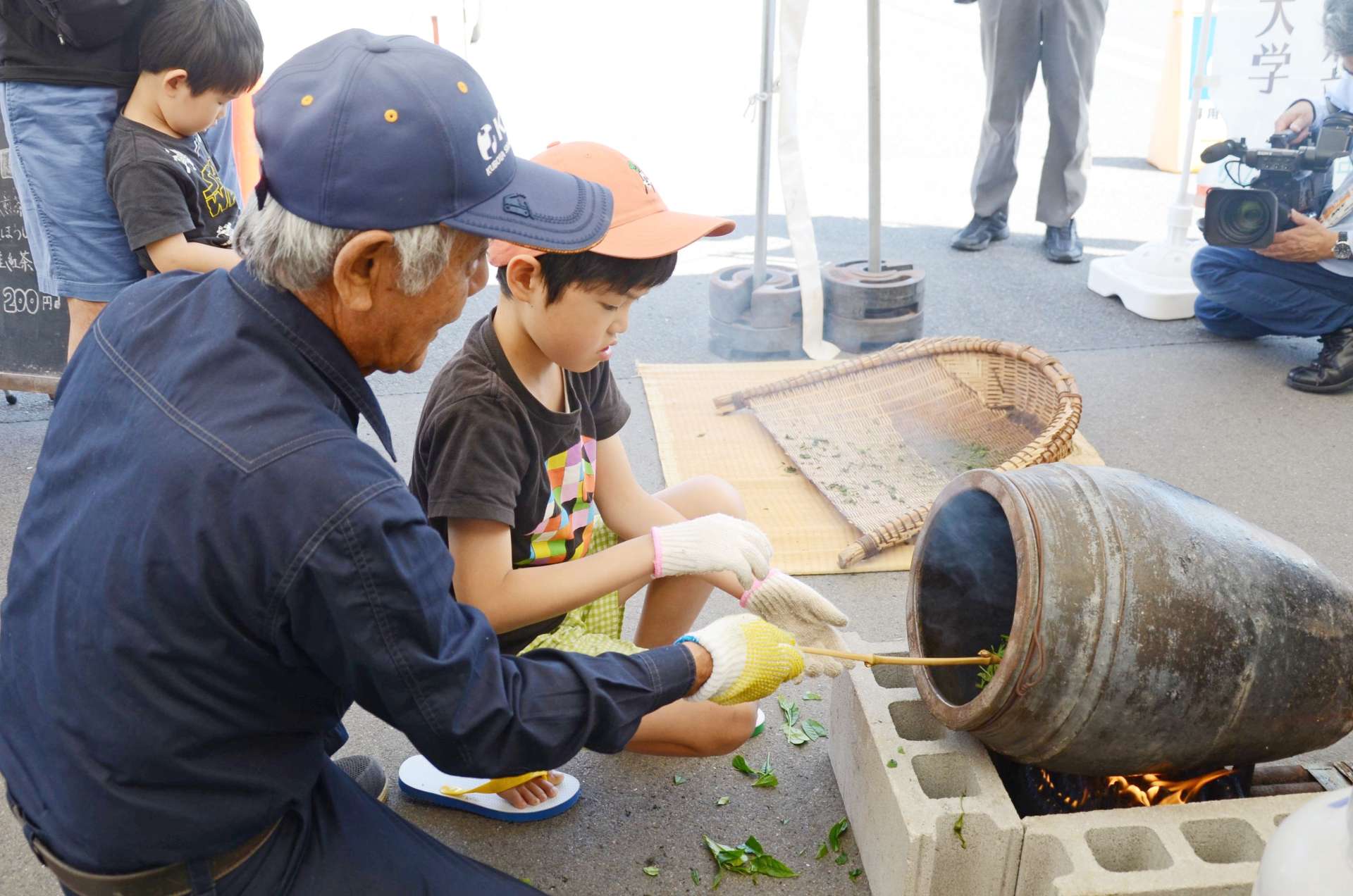 〈資料写真〉陶器のかめ（はんず）で茶の葉をいり蒸す「はんず茶」づくりを体験する子供ら