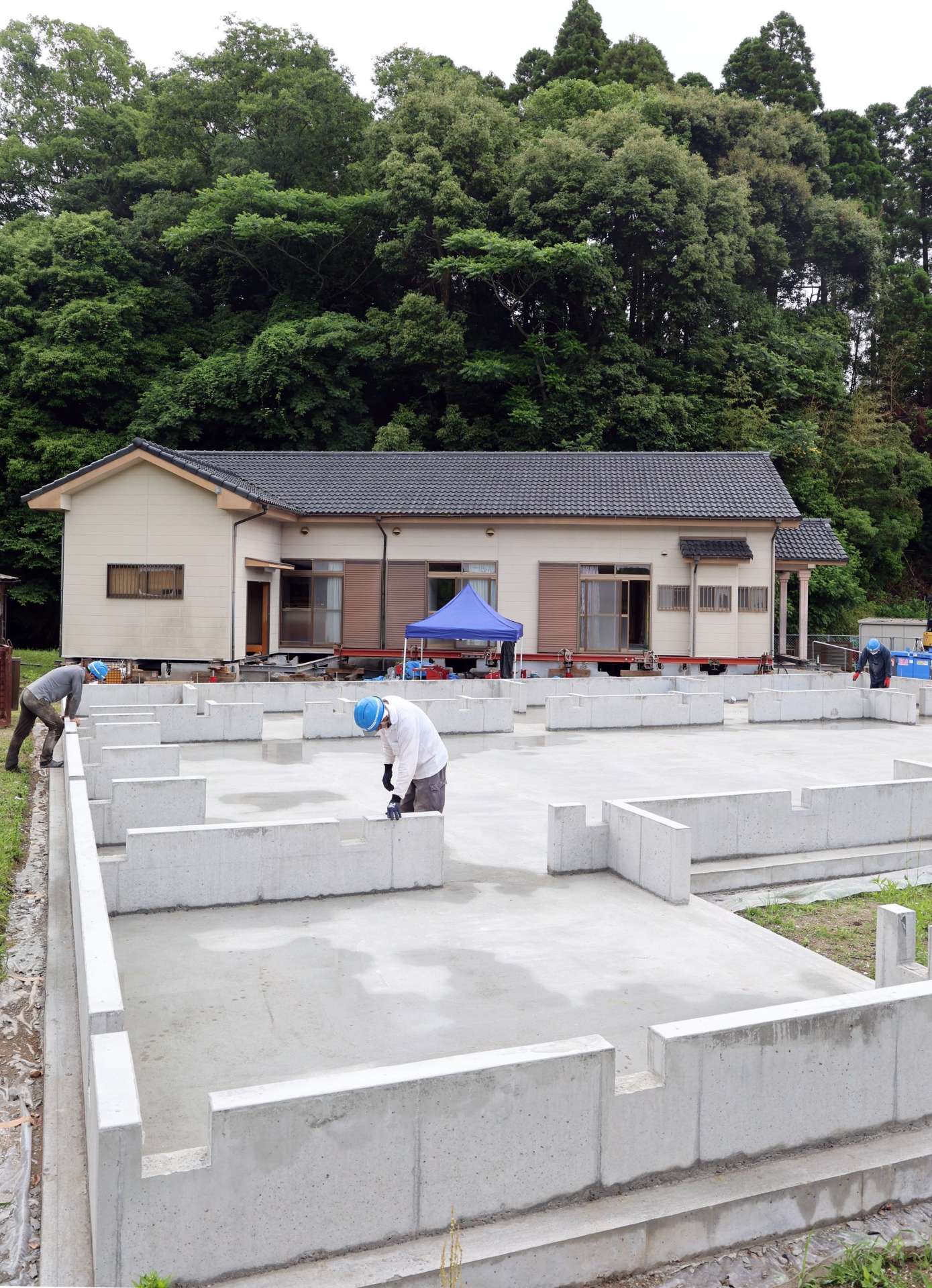 〈別カット〉背後に山が迫った喜入自治会館を曳家で移設するため設置された土台（手前）＝２０日、薩摩川内市平佐町