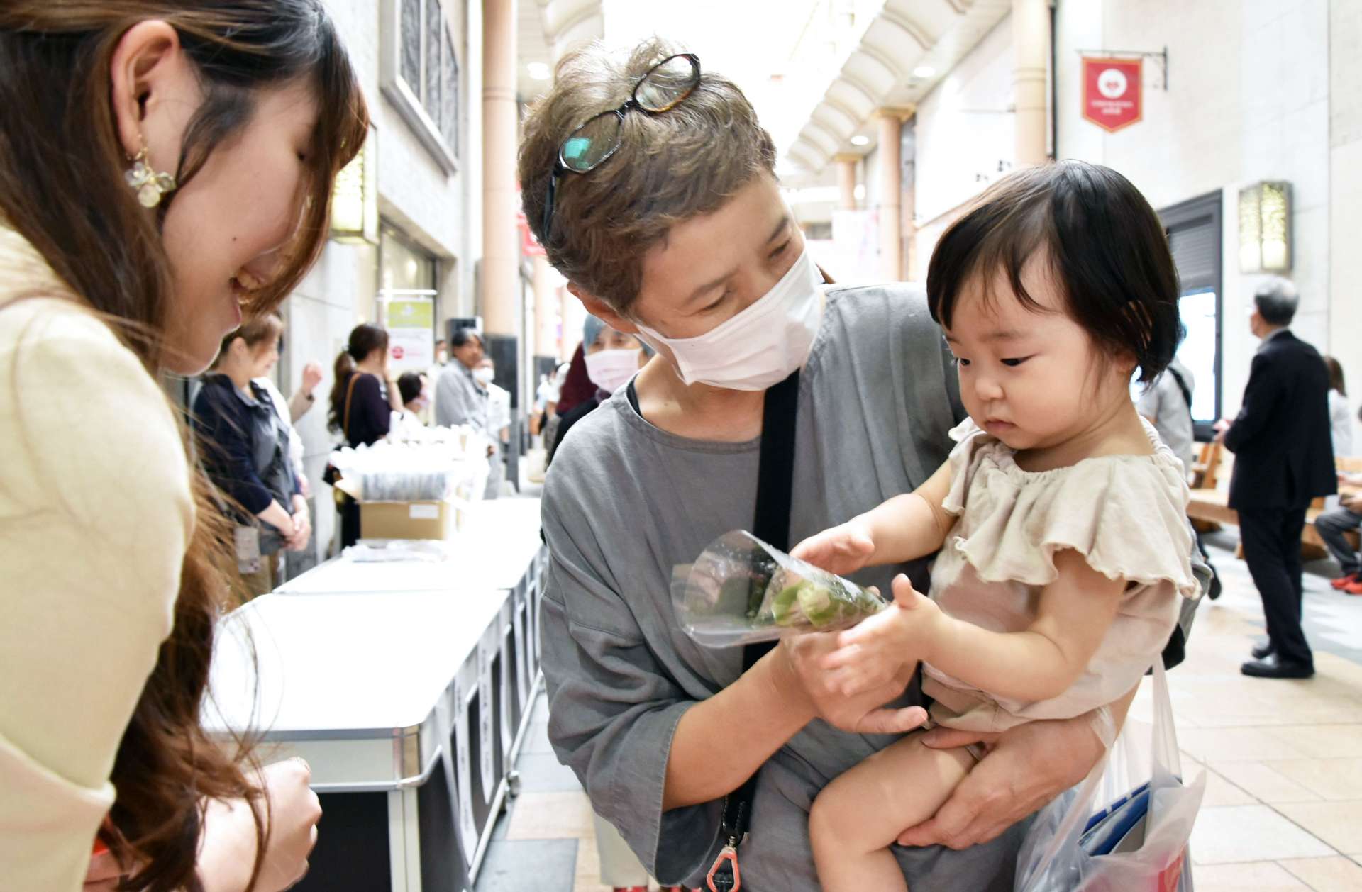 スズランを受け取る買い物客＝２５日、鹿児島市金生町