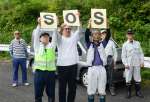 ドローンに向かって「ＳＯＳ」のボードを掲げる薬師集落の住民＝２５日、さつま町永野