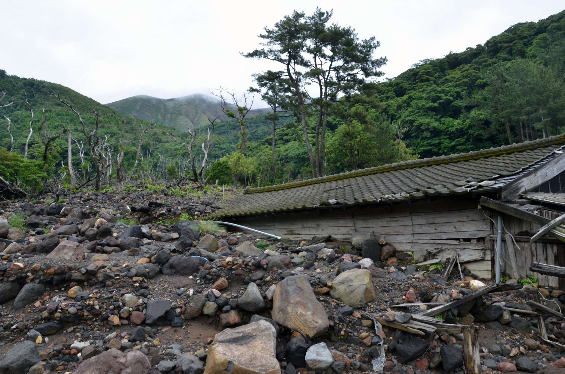 １０年前の火砕流と土石流で埋まった家屋。奥は新岳＝１９日、屋久島町口永良部島