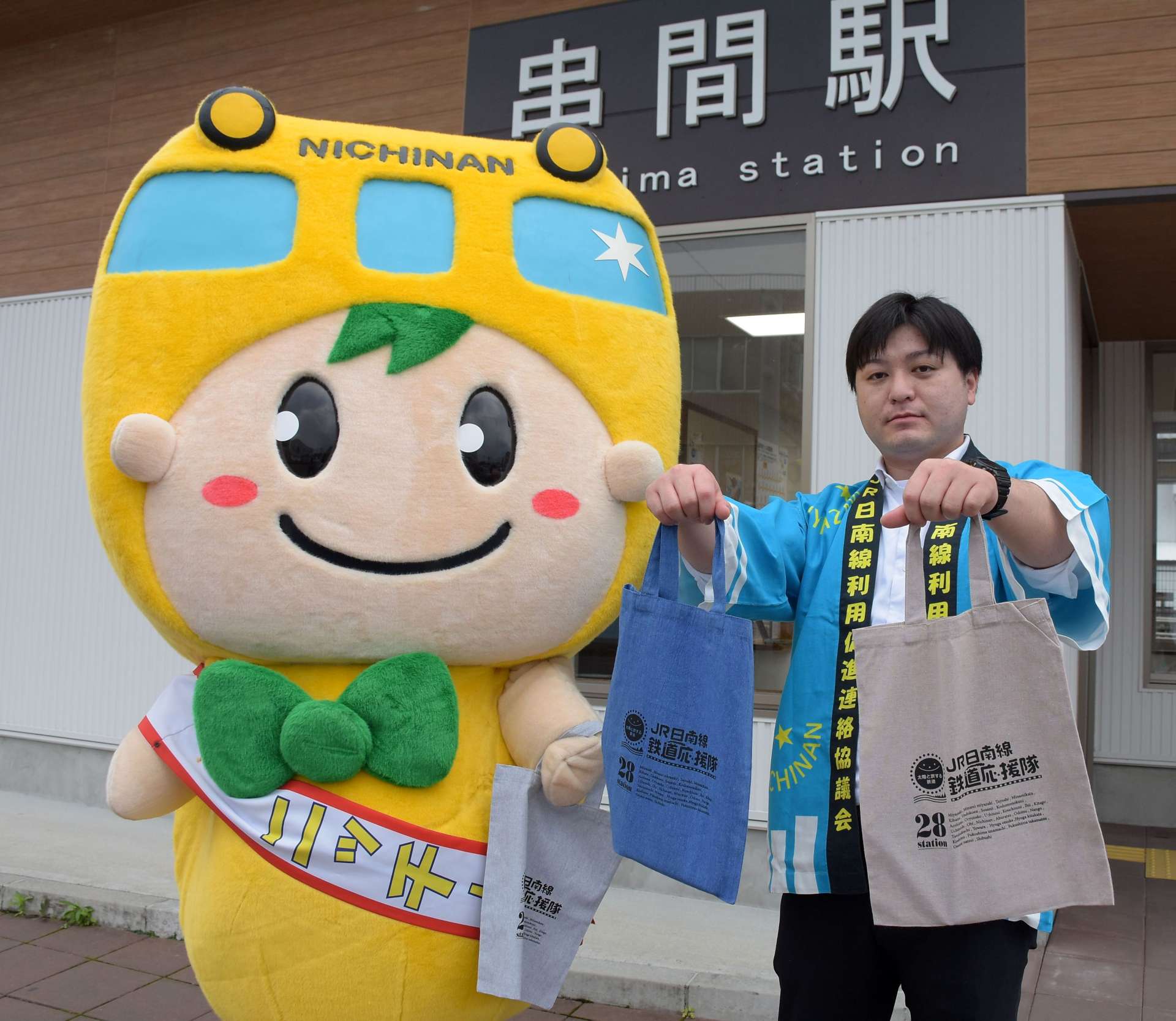 ＪＲ日南線鉄道応援隊をＰＲする日南線イメージキャラクター「ニッチー」（左）と串間市職員＝同市の串間駅