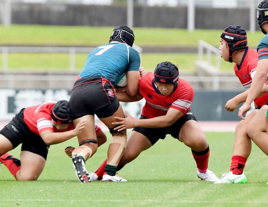２人がかりのタックルで相手を止める加治木工の選手＝白波スタジアム