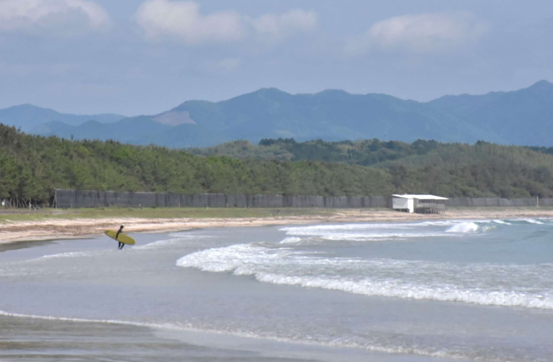 長い砂浜が続く脇本海岸。初夏はサーファーや潮干狩り客が訪れている＝阿久根市