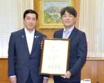 表彰を受ける高木稔文法人本部長（右）＝３日、県庁