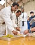 竹を使った飼料を手に取るインドの視察団＝薩摩川内市の鹿児島大学入来牧場