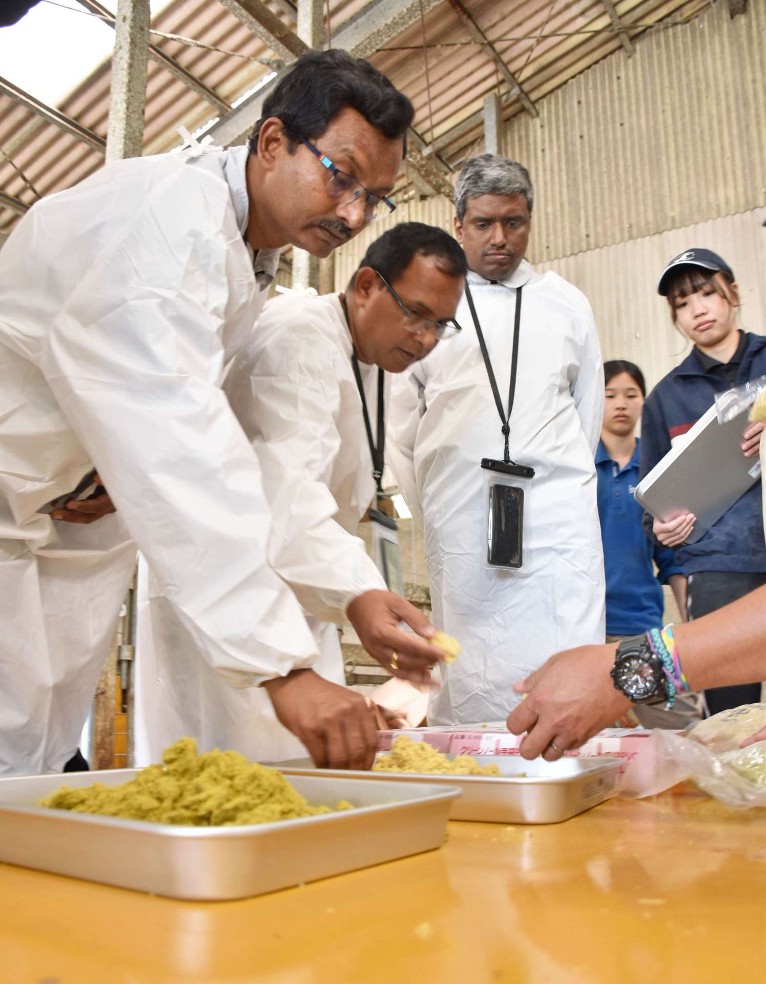 竹を使った飼料を手に取るインドの視察団＝薩摩川内市の鹿児島大学入来牧場