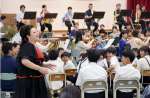 鹿児島交響楽団の演奏と隈元奈津希さんの歌声に聞き入る児童生徒＝志布志市の伊崎田小体育館