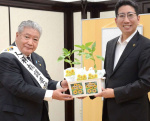 下鶴隆央市長にヒマワリの苗を贈る鹿児島人権擁護委員協議会の口羽勝法会長＝２日、鹿児島市役所