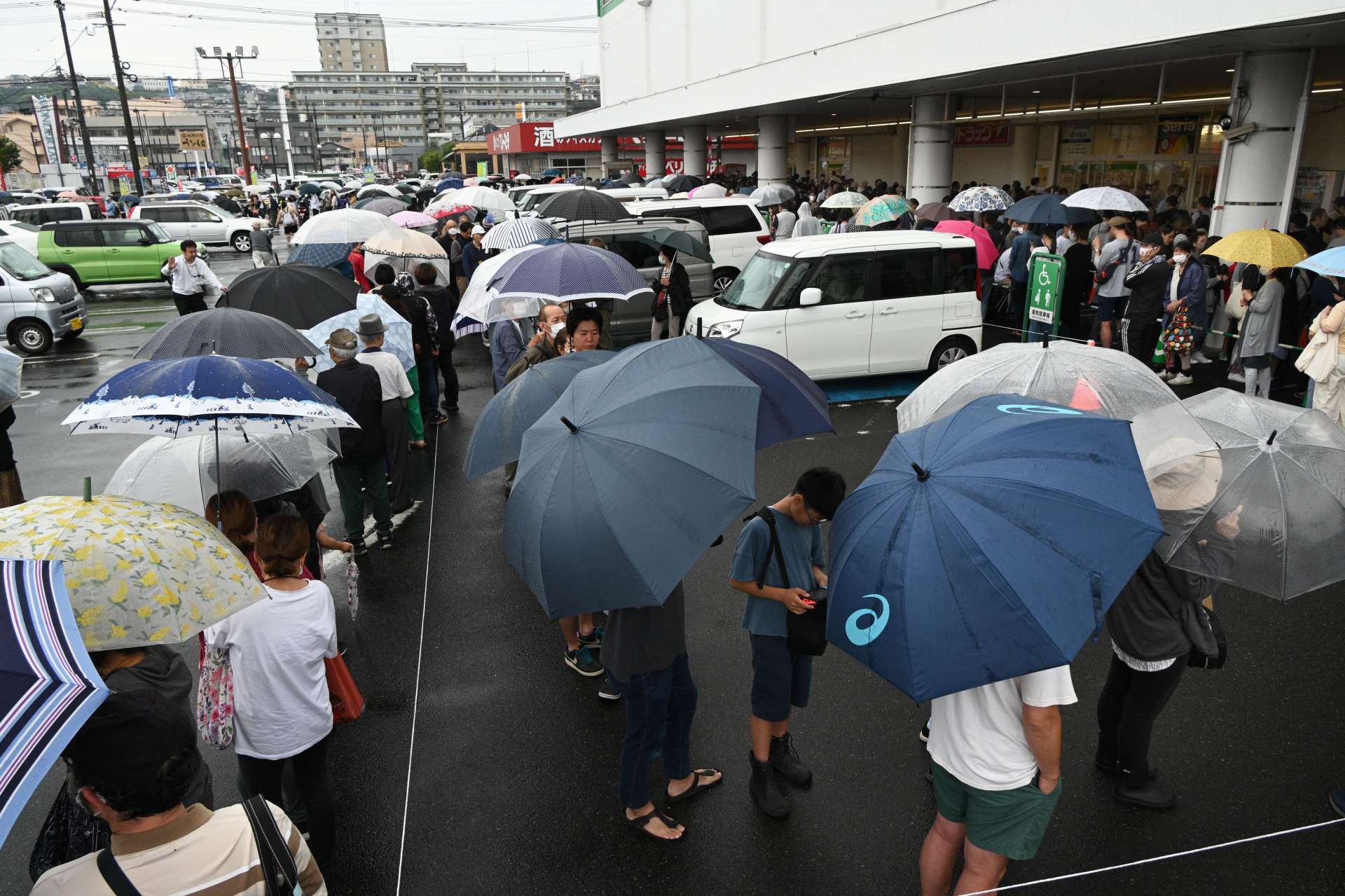 屋外駐車場にまで延びた備蓄米目当ての列＝８日午前９時２０分ごろ、鹿児島市のサンキュー新栄店