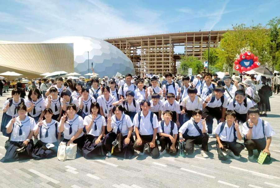 大屋根リングの近くで記念撮影する出水中学校の生徒たち＝大阪市（同校提供）