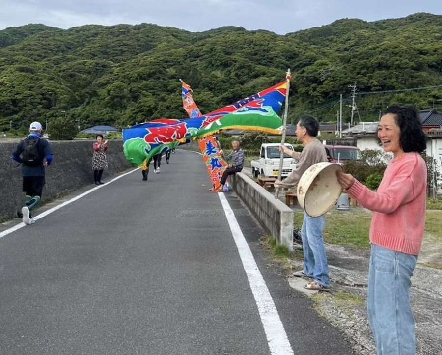 大漁旗を振ってランナーを応援する地元漁師のみなさん＝５月１１日、薩摩川内市下甑手打