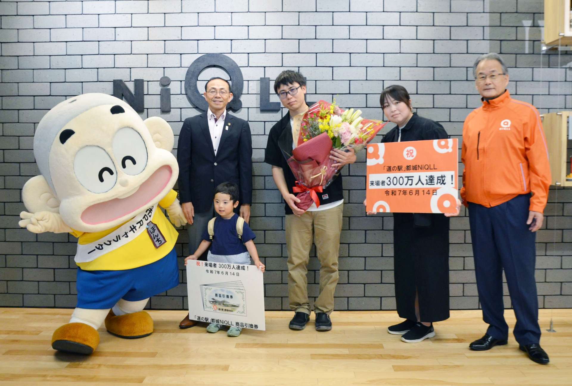 記念セレモニーで記念品や花束を受け取る齋藤青馬さん（中央）ら家族＝１４日、都城市都北町