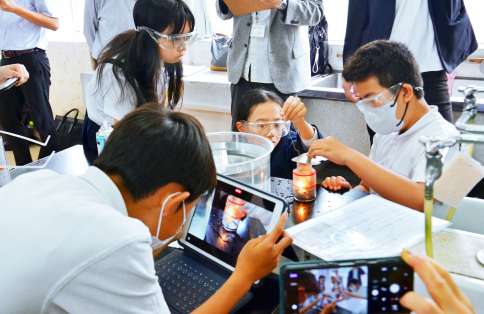 燃焼実験の様子をタブレットで撮影し記録する児童ら＝鹿児島市の田上小学校