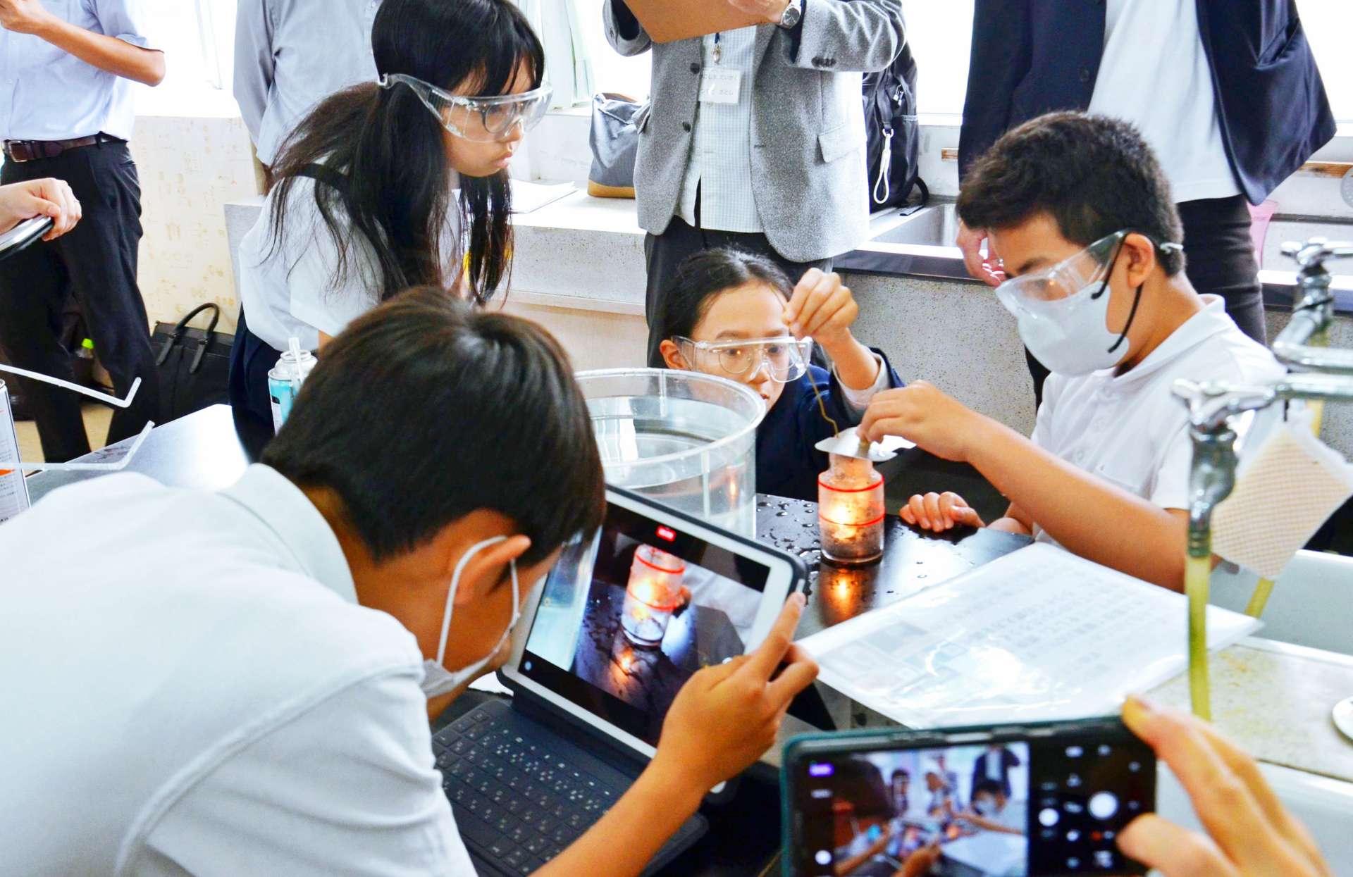 燃焼実験の様子をタブレットで撮影し記録する児童ら＝鹿児島市の田上小学校