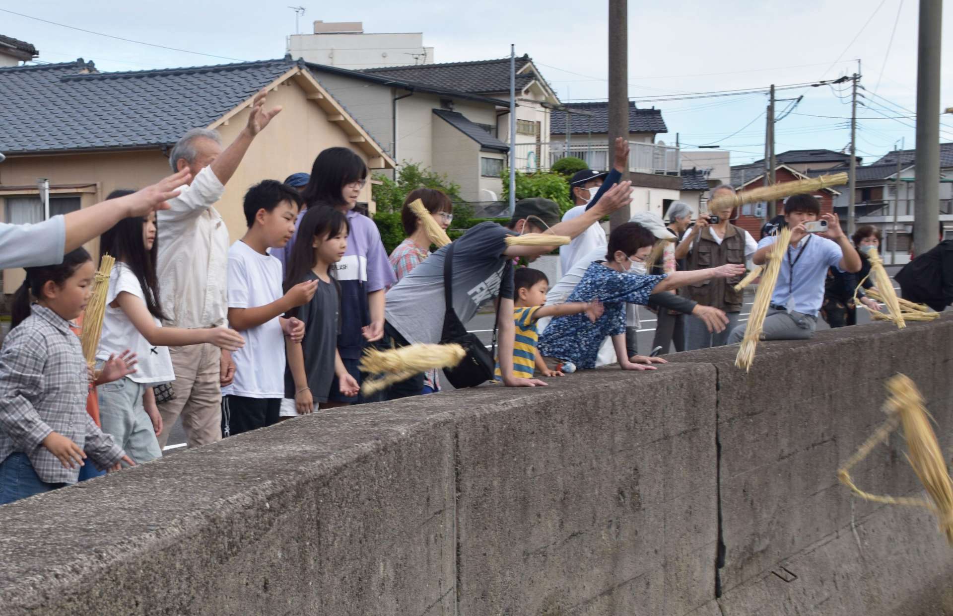 安全を祈願し、川に団子を投げる住民＝１１日、いちき串木野市北浜町の五反田川
