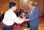 〈資料写真〉「定年祝う会」で教え子から記念の盾を受け取る塩瀬さん（右）＝１９９９年７月、鹿児島市
