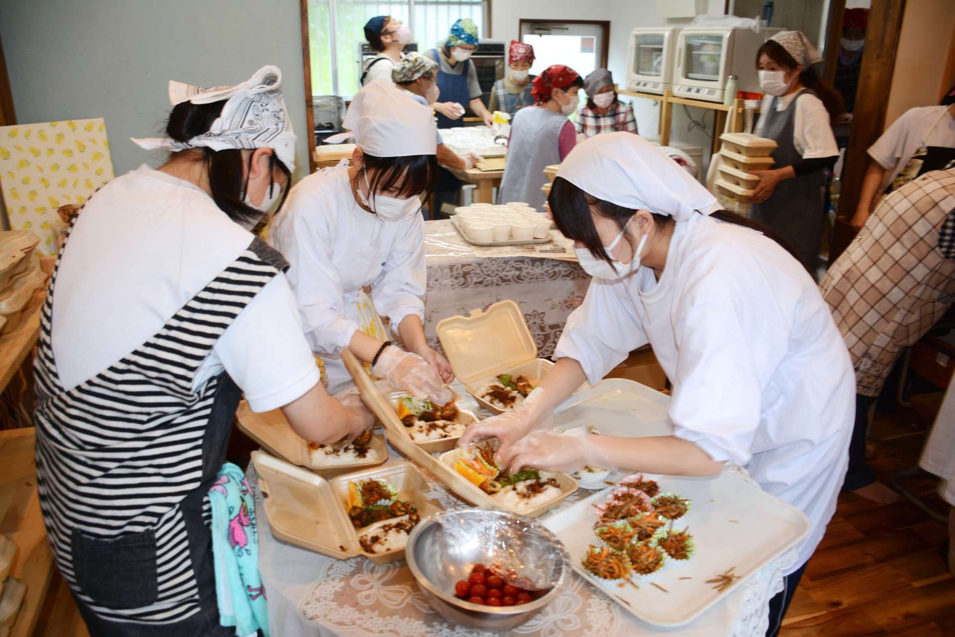 おかずを弁当箱に詰める薩南工業高校の生徒ら＝南九州市知覧町郡