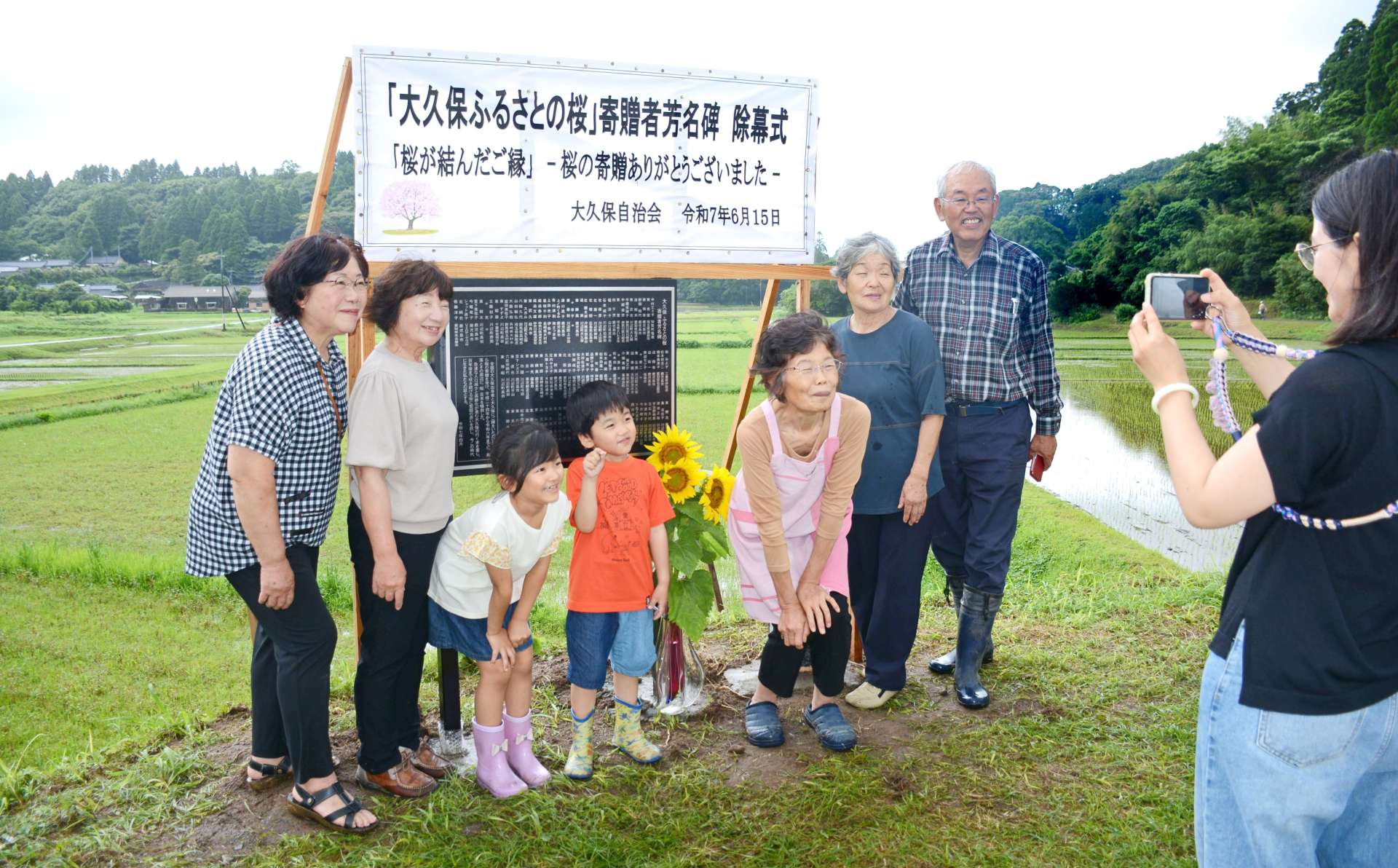 記念碑前で写真を撮る住民ら＝南九州市川辺町本別府