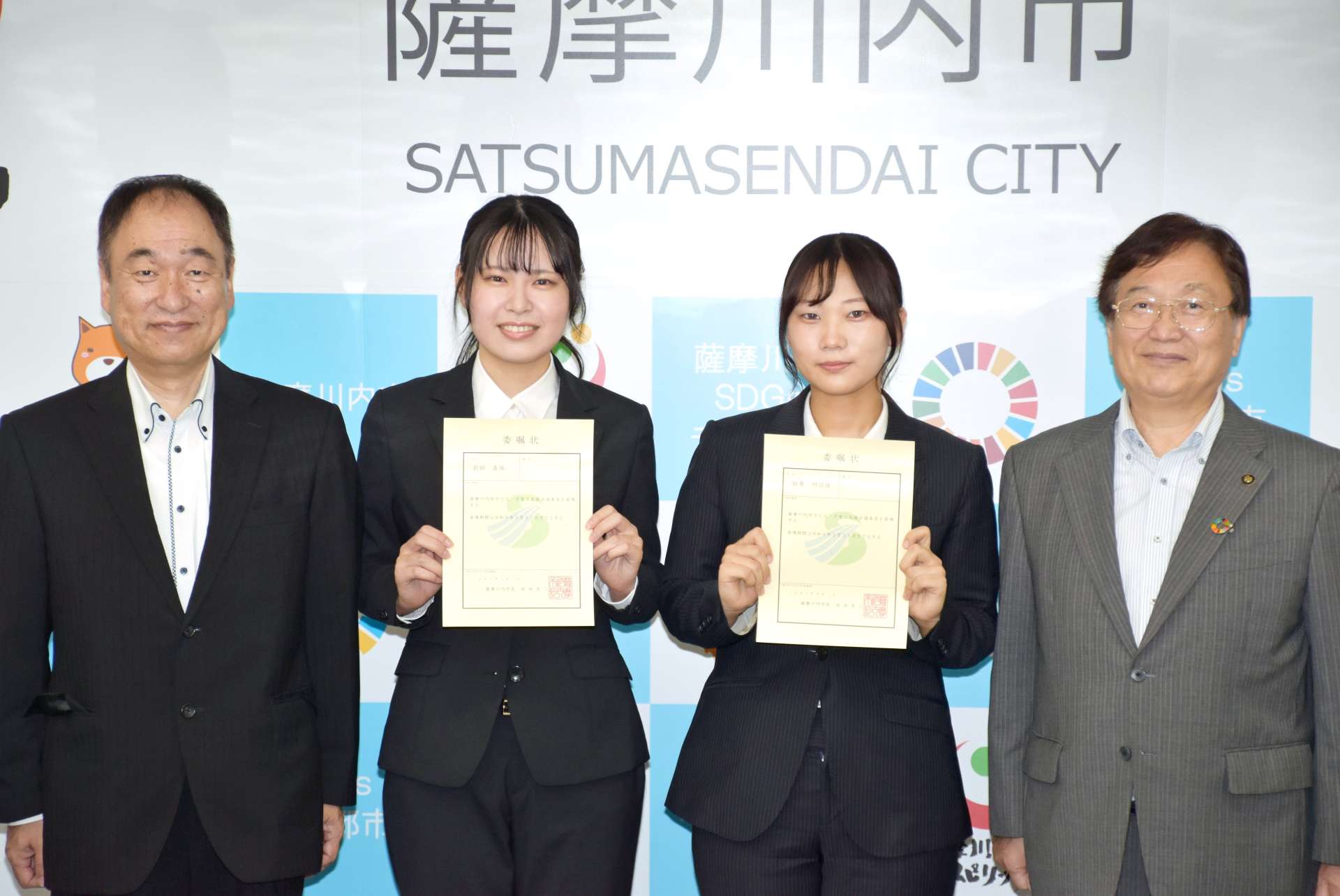 子ども・子育て支援会議委員に委嘱された鹿児島純心大学の鈴東明日佳さん（右から２人目）と前田喜保さん（同３人目）＝薩摩川内市役所