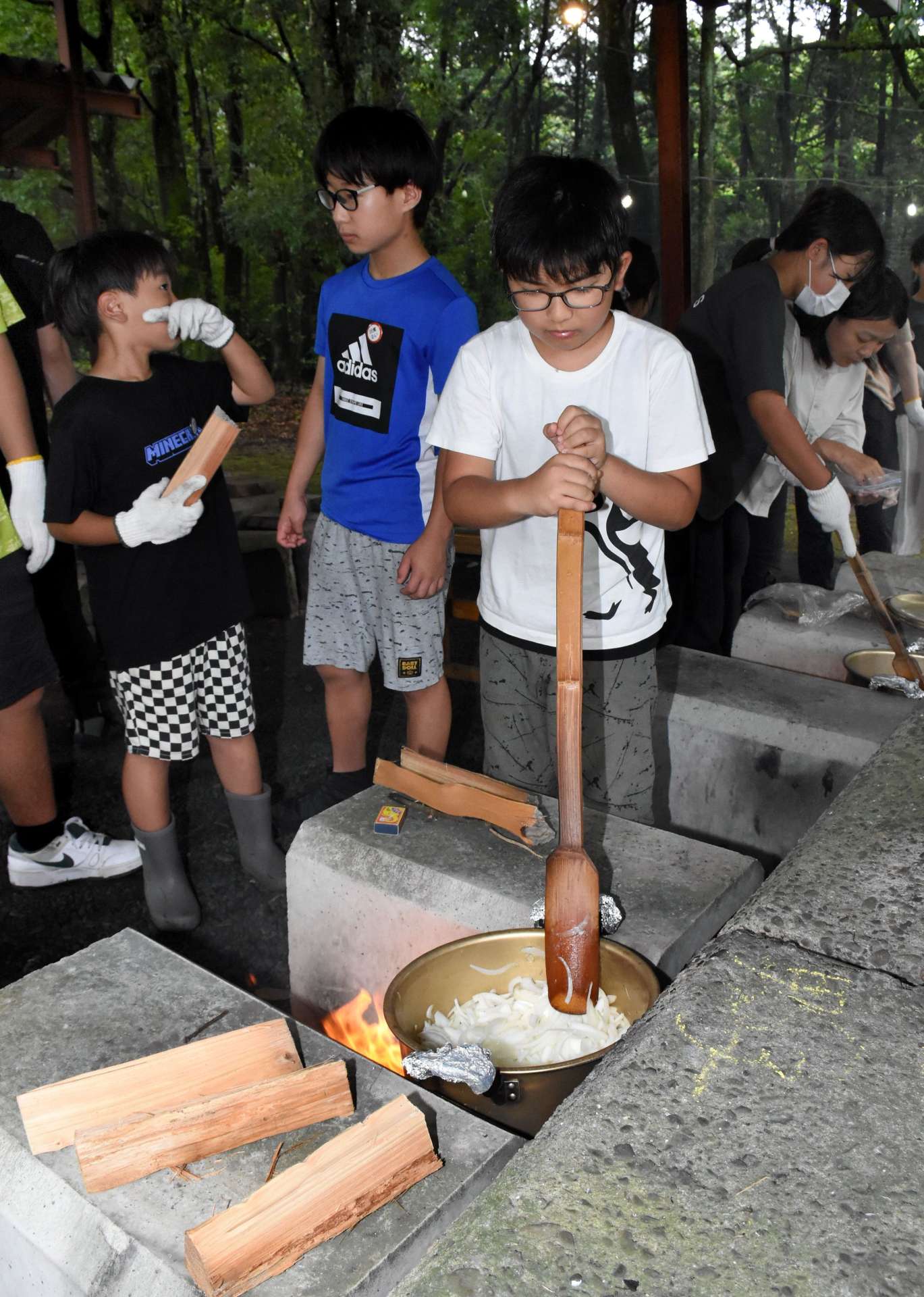 カレーの野菜を炒める子どもたち＝出水市青年の家