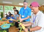収穫したトウモロコシの皮をむく短期留学生ら＝伊佐市の伊佐農林高校