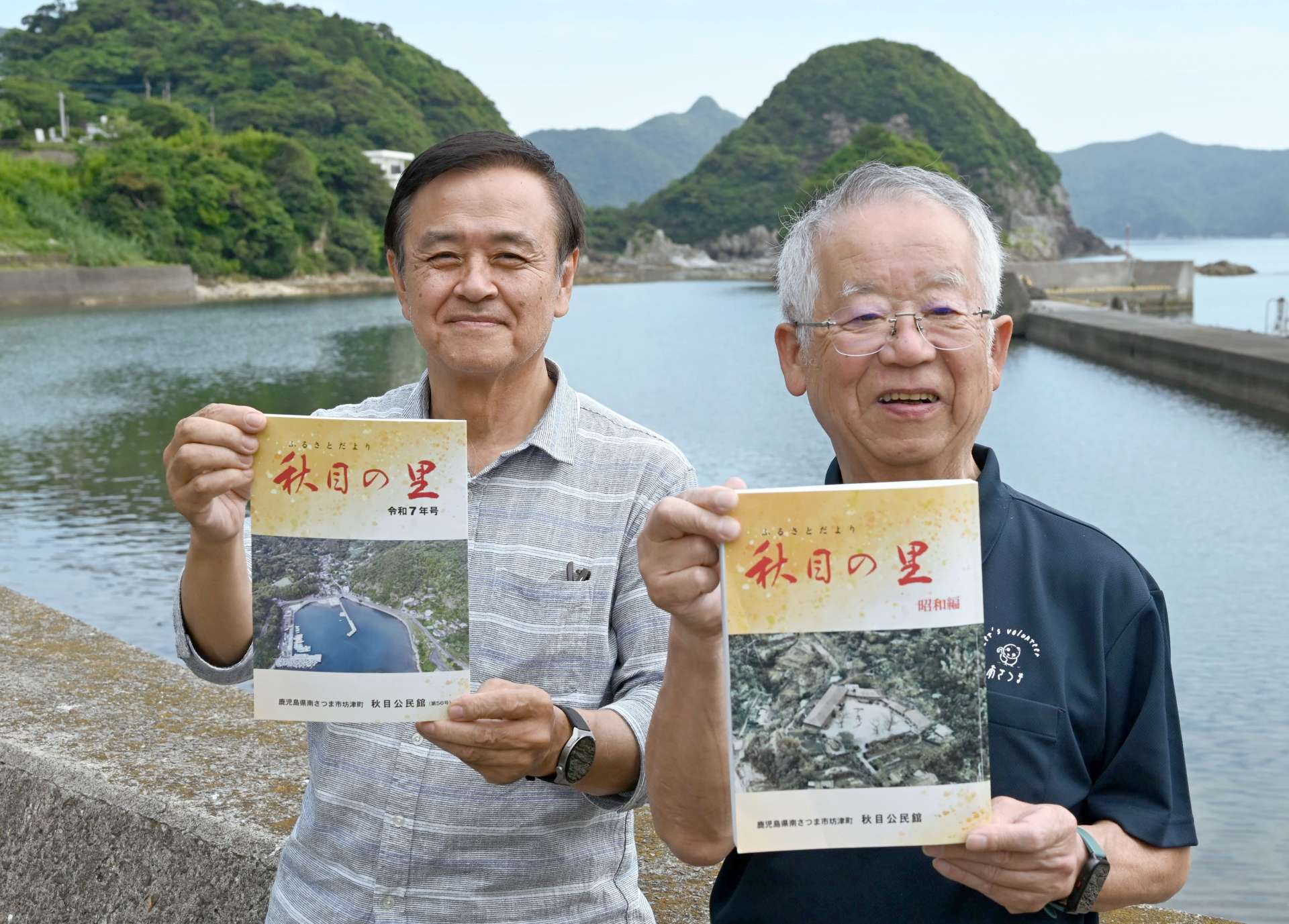 「秋目の里　昭和編」を手にする〓行孝二さん（右）と最新号を持つ斎藤治男さん＝南さつま市坊津町秋目