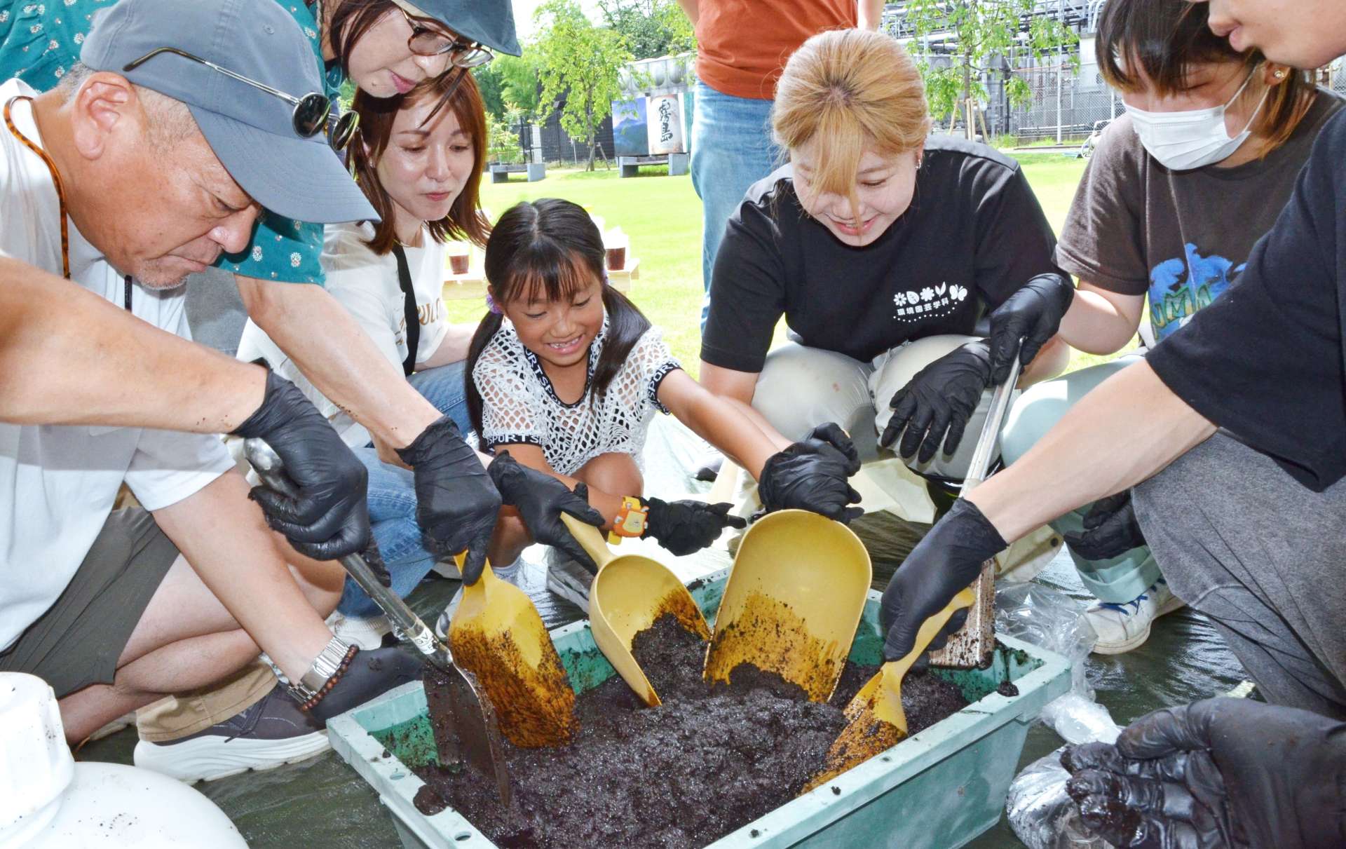 焼酎かすとコーヒー豆かすを混ぜ合わせる作業に挑む参加者＝２１日、都城市志比田町