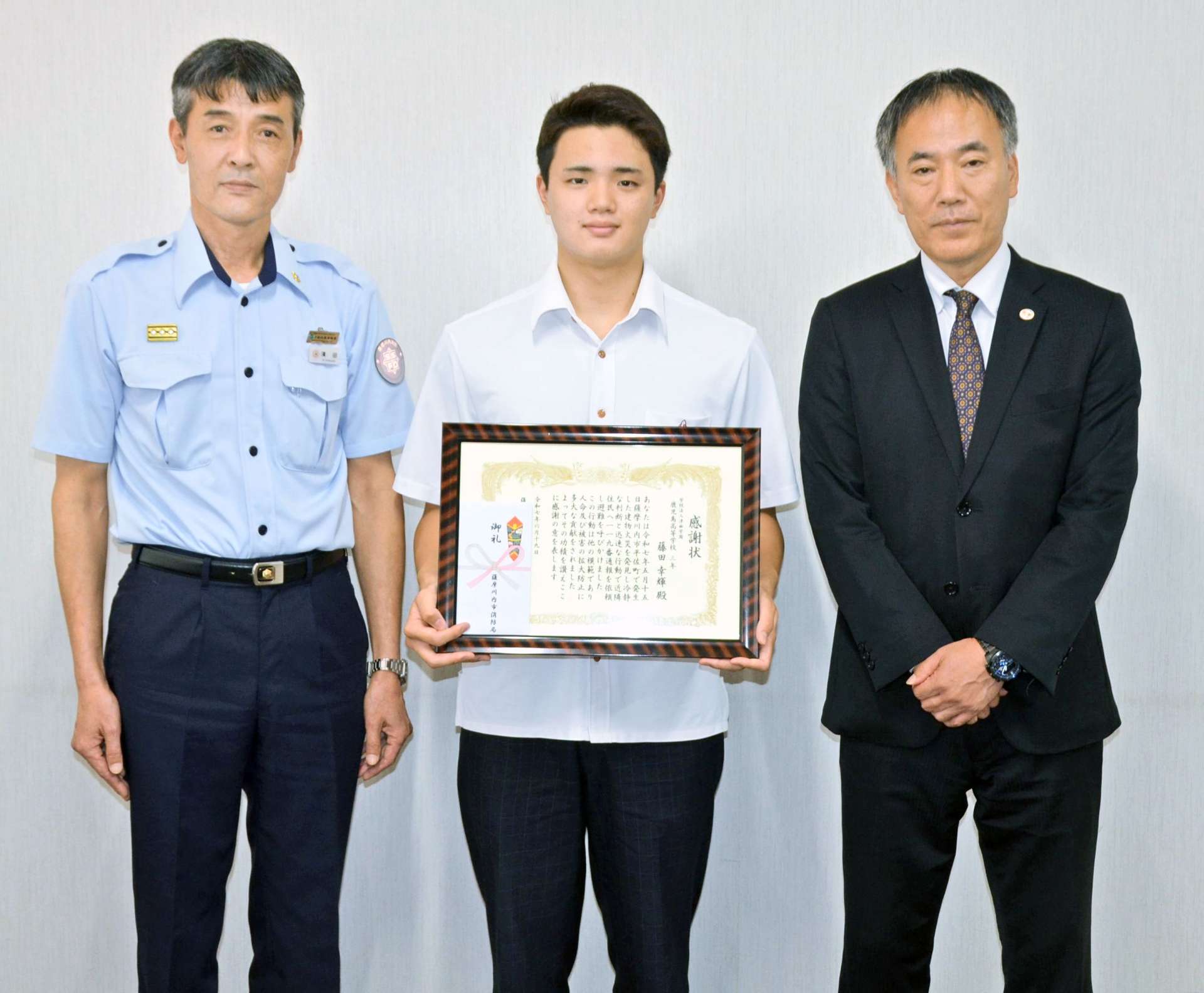 薩摩川内市中央消防署の浜田浩署長（左）から感謝状を受けた藤田幸輝さん（中央）＝鹿児島市の鹿児島高校