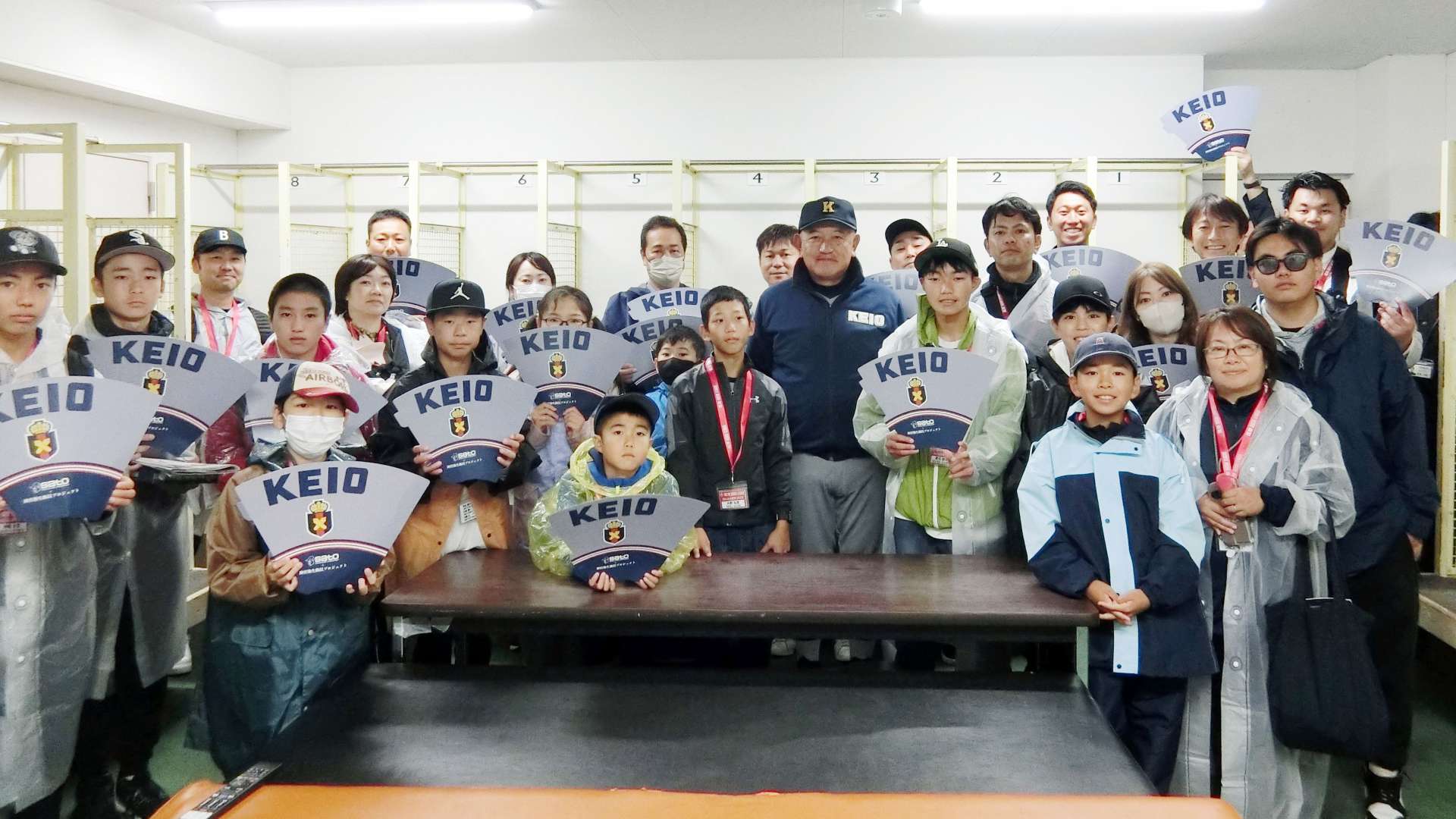 慶応の堀井哲也監督と一緒に記念写真に収まる子供たち＝東京都