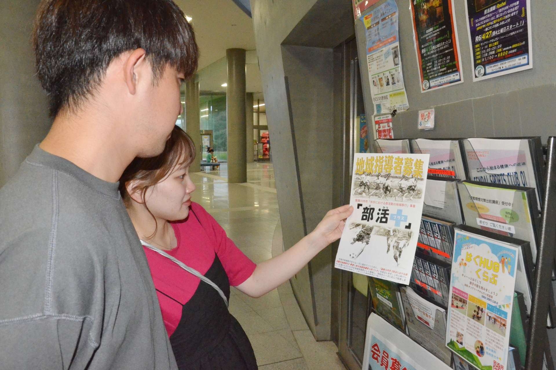 部活動の指導者を募集するチラシを手に取る市民＝１５日、薩摩川内市のサンアリーナ川内
