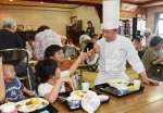子どもたちと歓談する鹿児島サンロイヤルホテルの天川伸也洋食部料理長＝鹿児島市宮之浦町の子ども食堂「宮っ子」
