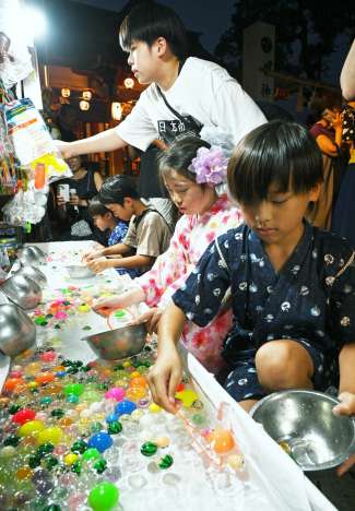 浴衣姿でスーパーボールすくいを楽しむ子供＝１日午後８時、鹿児島市清水町の八坂神社