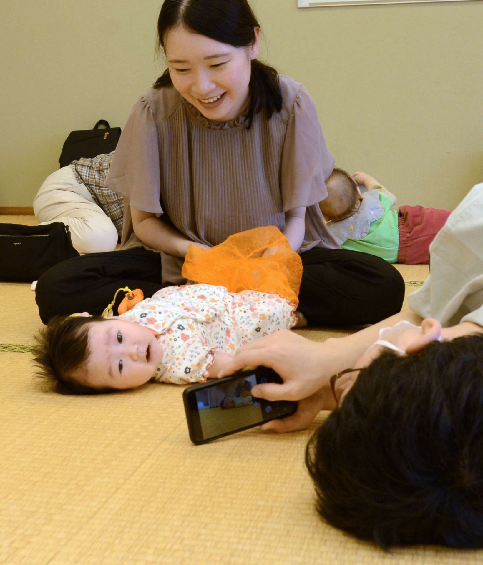 赤ちゃんの一瞬の表情を捉えようと撮影に奮闘する参加者＝３日、鹿児島市東部親子つどいの広場なかまっち