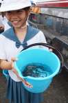 マダイの稚魚が入ったバケツを手にする平川小学校の児童＝４日、鹿児島市平川町の平川ヨットハーバー