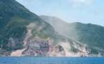 震度５強の地震が２回あった直後の悪石島西側。崖崩れや落石が起き、土煙が舞う＝６日午後２時すぎ、十島村（第１０管区海上保安本部提供）