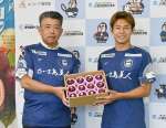 ＪＡ鹿児島経済連の串町英明常務理事（左）からパッションフルーツを贈られる鹿児島ユナイテッドＦＣの河村慶人選手＝ユニータ